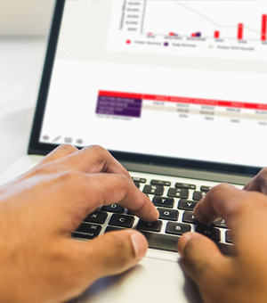 A pair of hands is typing on a laptop computer