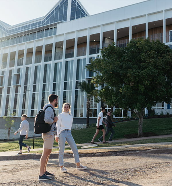 ACU students walking across campus, casting shadows on the ground