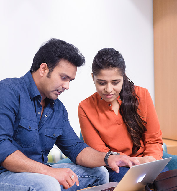 A woman is shown something on a laptop by a man