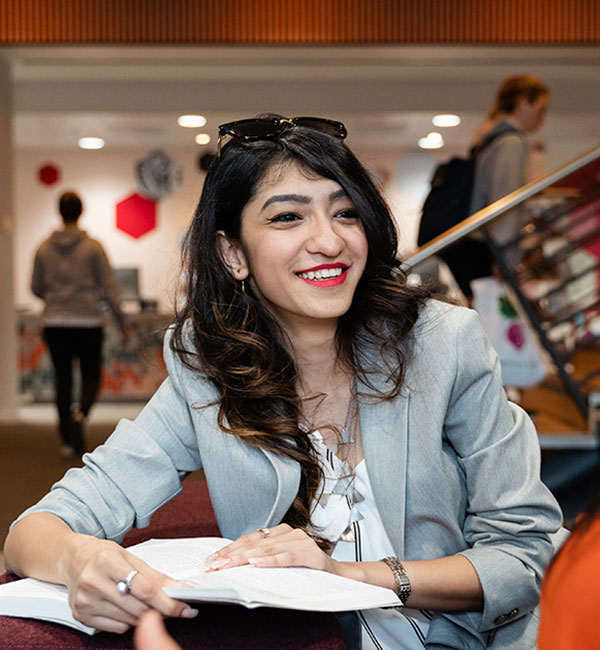 An ACU student smiles warmly while sitting at a desk in the ACU library