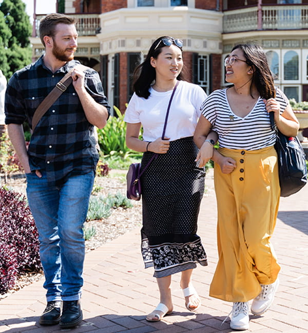 Three students cross an ACU campus outdoors