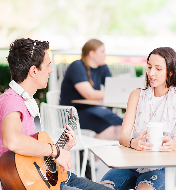 ACU music student playing a guitar on campus