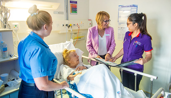 ACU students and supervisor providing care to an elderly lady in hospital
