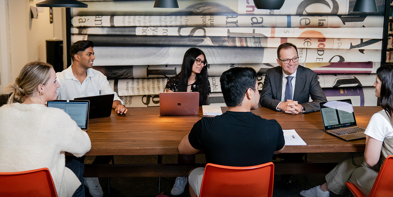 Professor Zlatko Skrbis chats to students sitting around a table